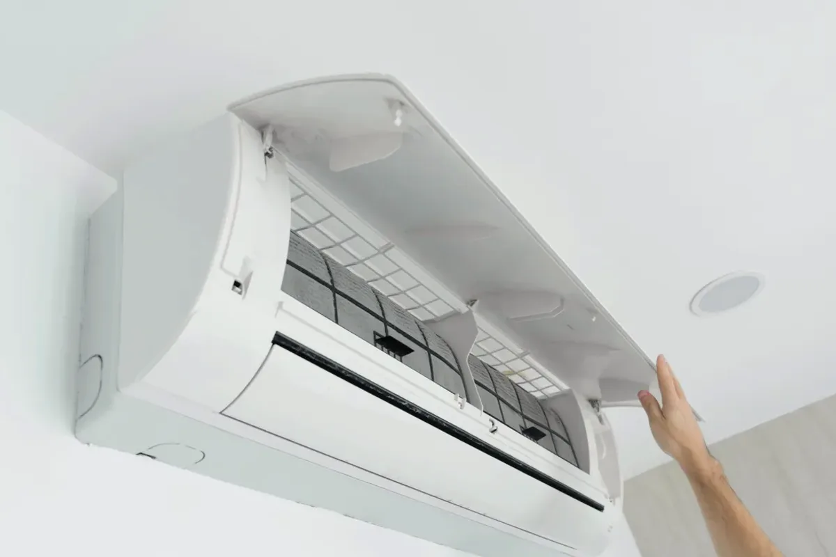 Hand opening the cover of a wall-mounted ductless air conditioner